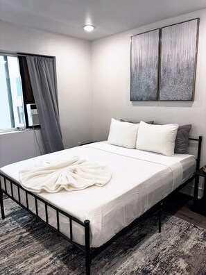 A modern bedroom with a bed, a window with curtains, a wall-mounted air conditioner, and two abstract paintings. - 2-bedroom apartment in tranquil Dallas with AC for your stay (Dallas)
