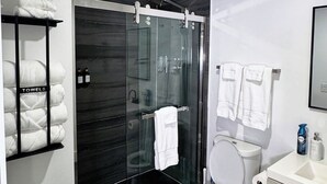Ein modernes Badezimmer mit Duschkabine aus Glas, Toilette, Waschbecken und Handtuchhalter.