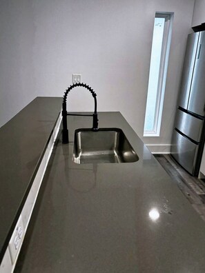 A kitchen with a stainless steel sink, a faucet, and a refrigerator. - 2-bedroom apartment in tranquil Dallas with AC for your stay (Dallas)