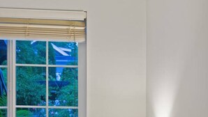 A bedroom with a bed, a window with blinds, a bedside lamp, and a view of greenery outside. - Cozy and Calm: Modern Studio with Private Entrance (Vancouver)