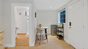 A compact kitchen with a dining area, a small window, and a door leading to another room. - Cozy and Calm: Modern Studio with Private Entrance (Vancouver)