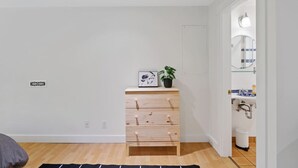 A room with a wooden dresser, a framed picture, a potted plant, and a bathroom visible through an open door. - Cozy and Calm: Modern Studio with Private Entrance (Vancouver)