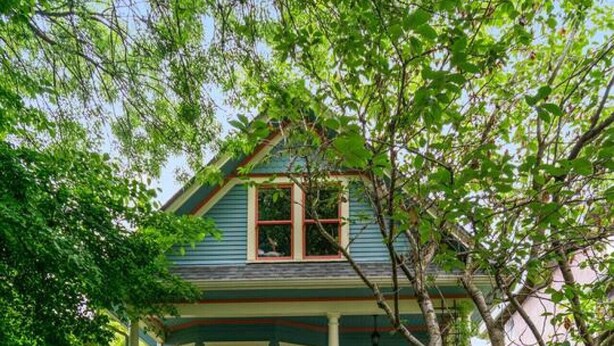 A two-story house with a porch, a front door, and a staircase leading to the entrance. - Cozy and Calm: Modern Studio with Private Entrance (Vancouver)