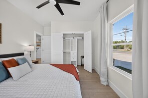 A bedroom with a bed, a ceiling fan, a wardrobe, and a window with a view of the outside. - Modern Brownsville Duplex Near Zoo & SPI (Brownsville)