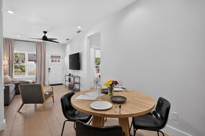 Un espace repas moderne avec une table ronde en bois, des chaises noires et un vase rempli de fleurs.