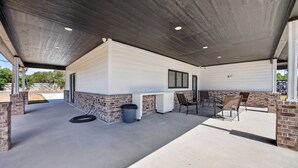 Ein überdachter Patio-Bereich mit Betonboden, Ziegelakzenten und einer weißen Außenwand.