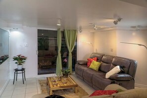 Ein Wohnzimmer mit einem braunen Ledersofa, einem Holztisch und einem grünen Vorhang.