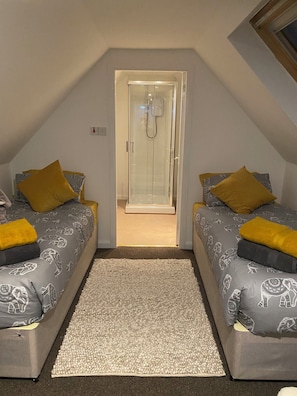 A room with two beds, a shower, and a carpeted floor. -  Cosy Cottage Sleeps 8 in Newburgh, Fife (Newburgh)