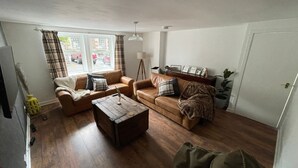 A living room with two sofas, a coffee table, a lamp, and a door. - Cosy Cottage Sleeps 8 in Newburgh, Cupar, Fife (Newburgh)