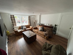 A living room with two sofas, a coffee table, a lamp, and a door. -  Cosy Cottage Sleeps 8 in Newburgh, Fife (Newburgh)