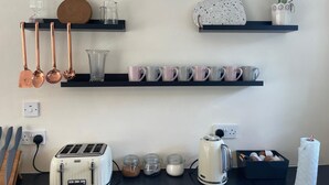 A kitchen with a toaster, kettle, and various mugs on shelves. - Cosy Cottage Sleeps 8 in Newburgh, Cupar, Fife (Newburgh)