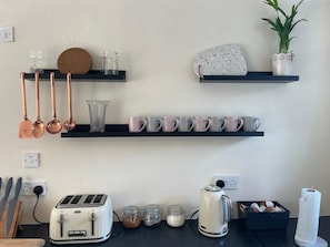 A kitchen with a toaster, kettle, and various mugs on shelves. -  Cosy Cottage Sleeps 8 in Newburgh, Fife (Newburgh)