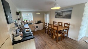A compact kitchen with a dining area, a washing machine, and a microwave. - Cosy Cottage Sleeps 8 in Newburgh, Cupar, Fife (Newburgh)