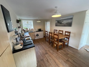 A compact kitchen with a dining area, a washing machine, and a microwave. -  Cosy Cottage Sleeps 8 in Newburgh, Fife (Newburgh)