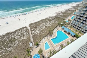 Ein Strandresort mit Schwimmbad, Strandliegen und Blick auf den Ozean.
