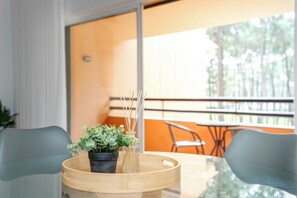 Ein modernes Zimmer mit Glastisch, zwei Stühlen, einem Blumentopf und einem Bambus-Tablett.