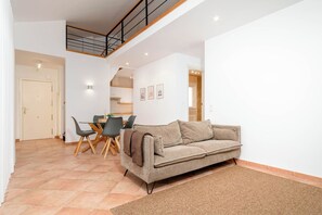 Ein moderner Wohnbereich mit Essplatz, einer Couch und einer Treppe, die in eine obere Etage führt.