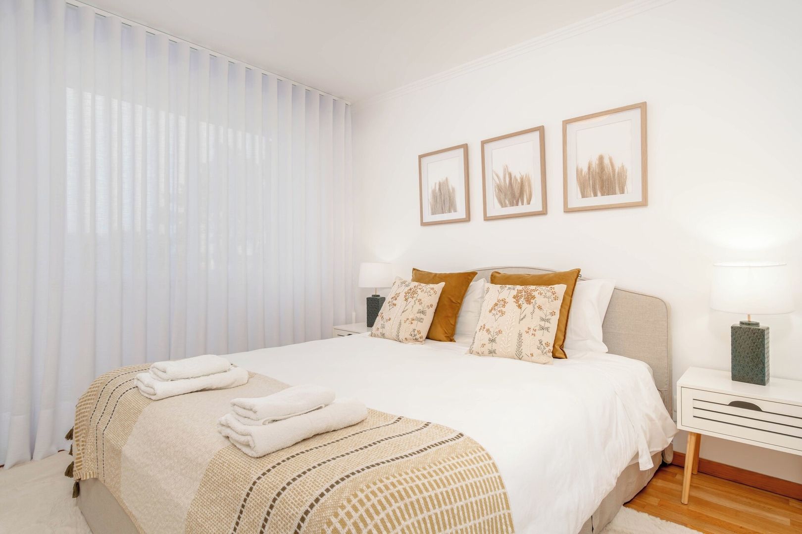 A hotel room with a bed, a nightstand, a lamp, and a window with blinds.