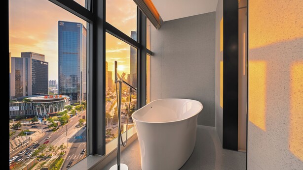 A modern bathroom with a large bathtub, a view of a cityscape through large windows, and a minimalist design. - Four Points By Sheraton Guangzhou Changlong Wanbo Business District (Guangzhou)