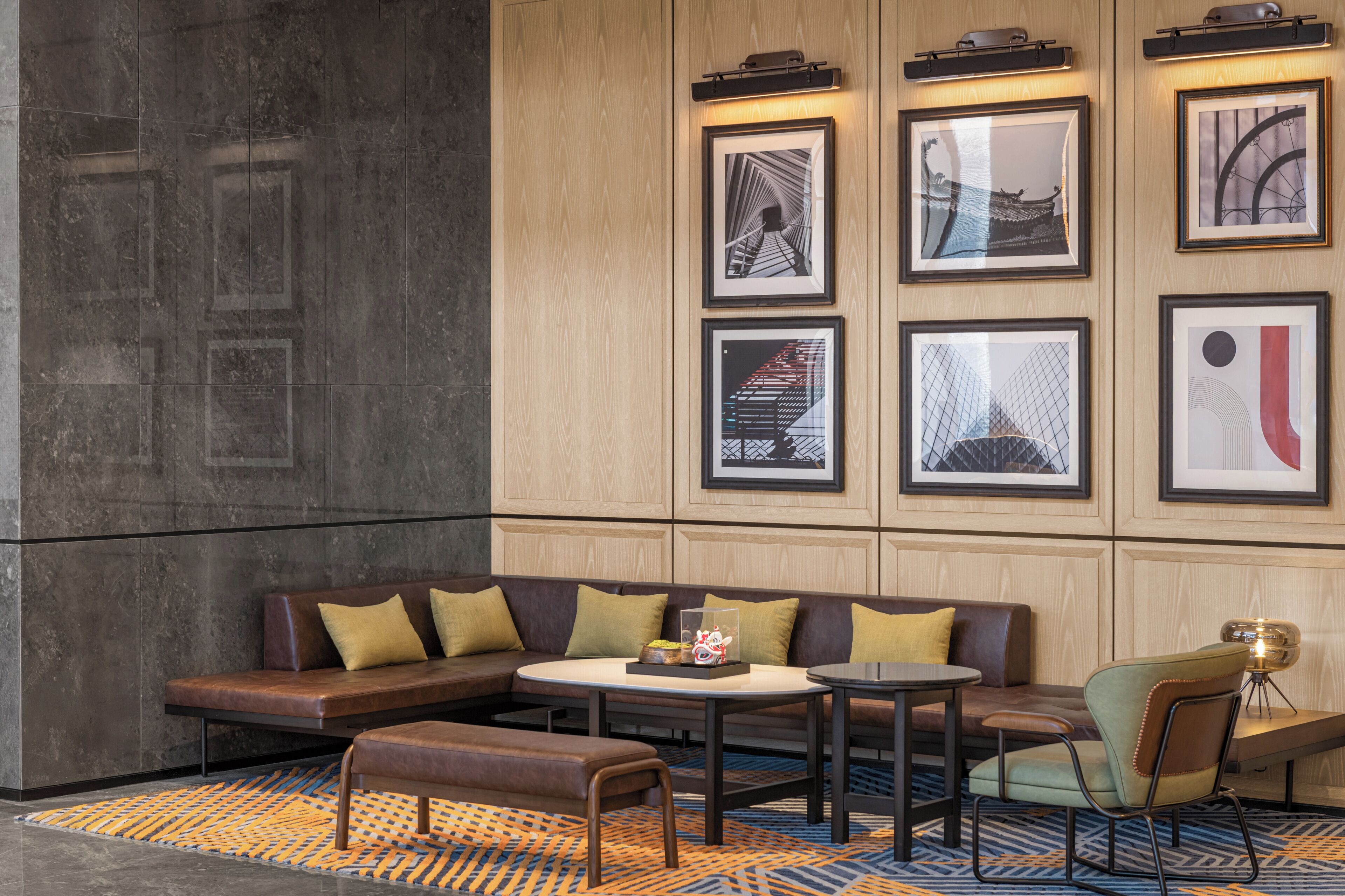 Un lobby moderno con un sofá modular, una mesa redonda y una silla pequeña.