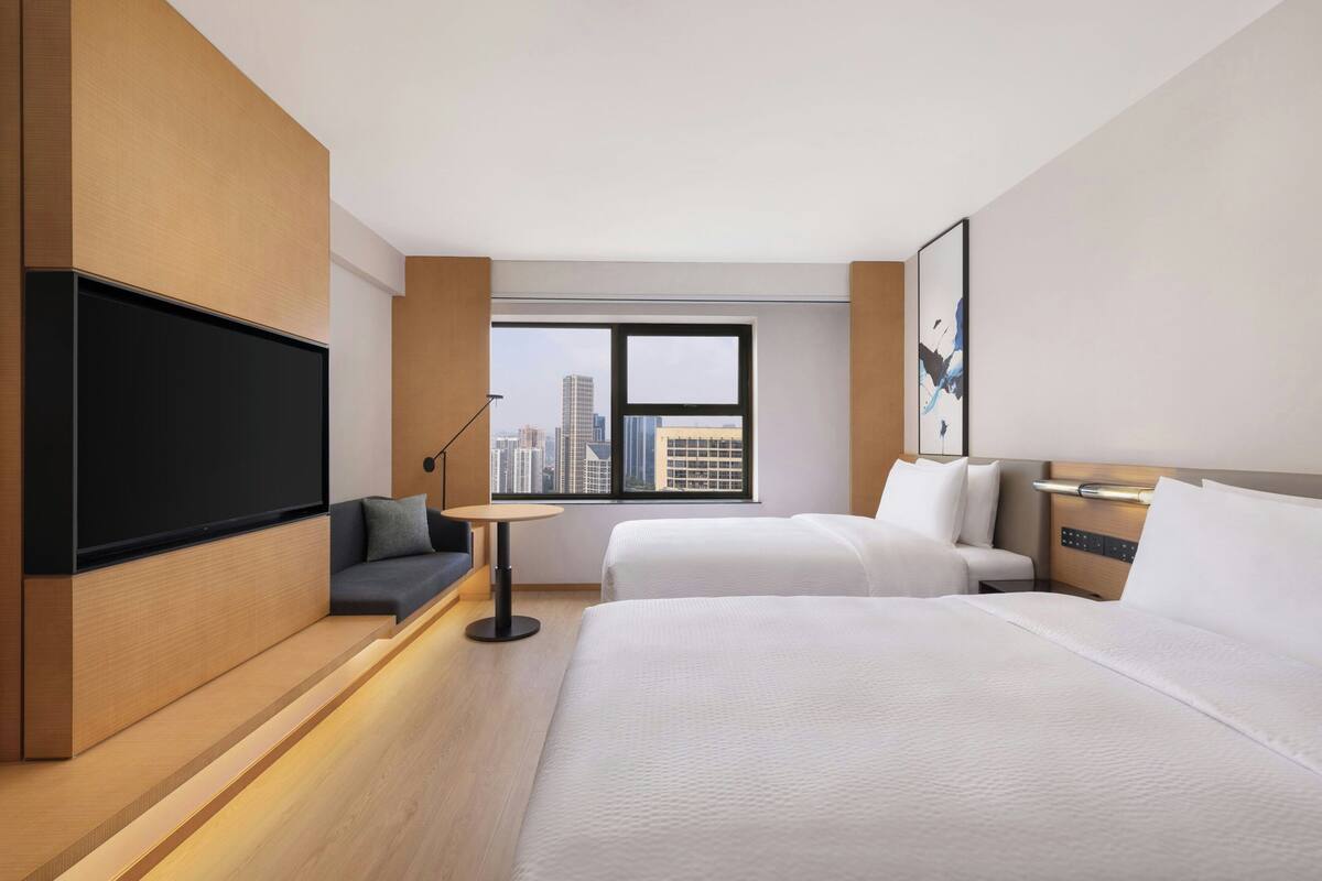A hotel room with a large bed, a sofa, a TV, and a city view.