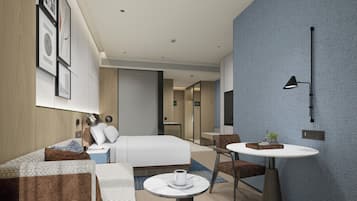 A modern hotel room with a bed, sofa, table, and a small desk.
