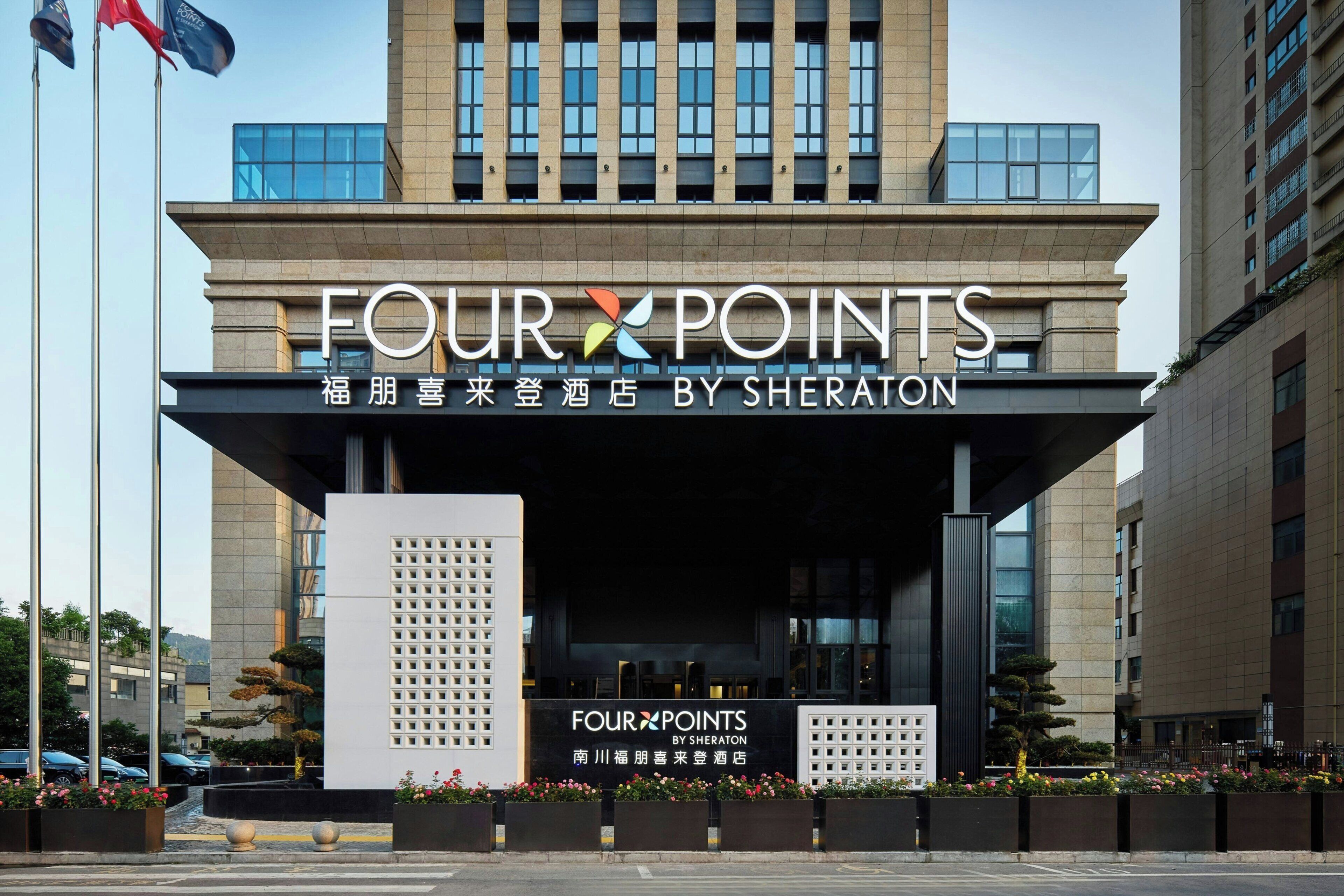 L’entrée d’un hôtel, avec une enseigne indiquant « FOUR POINTS BY SHERATON », et la façade moderne du bâtiment.