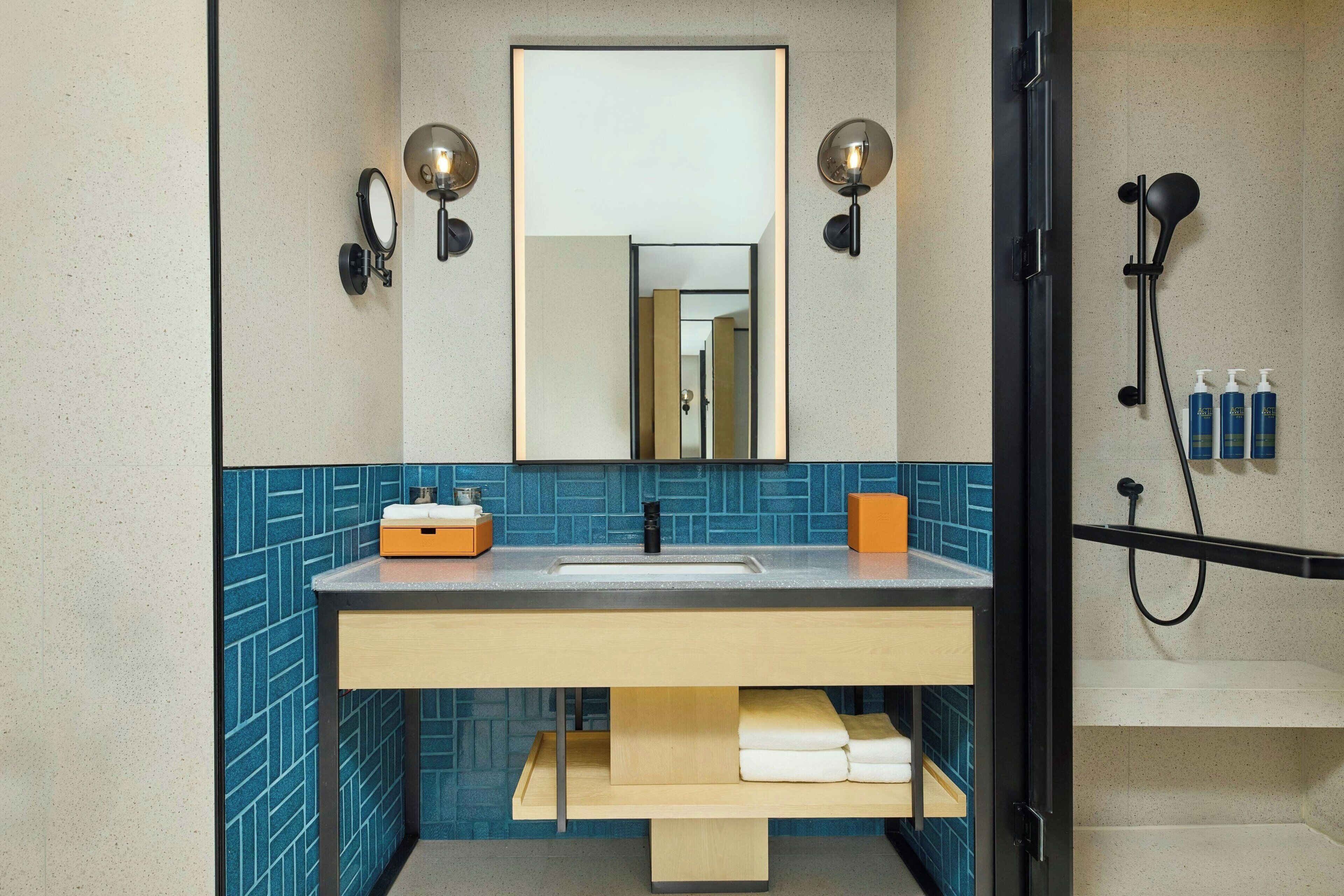 A bathroom with a sink, mirror, towel rack, and shower.
