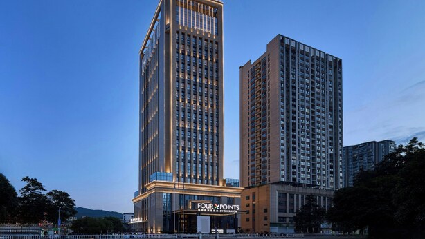 Un hotel alto con un letrero llamativo que dice 'FOUR POINTS' y 'DISEÑADO POR SHERATON'.