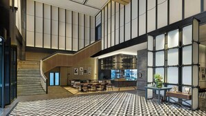 Un vestíbulo amplio con suelo de diseño geométrico, una escalera, zona de estar y un bar.