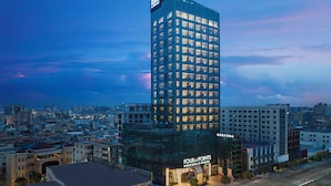 Un hotel moderno de gran altura con fachada de vidrio, varios pisos y una señalización llamativa.