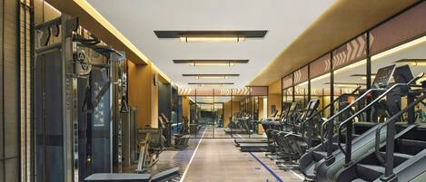 A gym with treadmills, weight machines, and a mirrored wall.