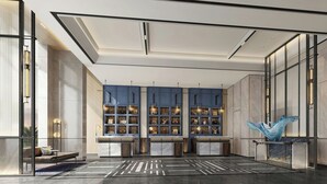 Un vestíbulo moderno con zona de estar central, mostrador de recepción y una escultura decorativa.