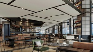 Un interior moderno con varias zonas de estar, incluyendo sofás y sillones, distribuidos alrededor de mesas y una zona de bar con estanterías.