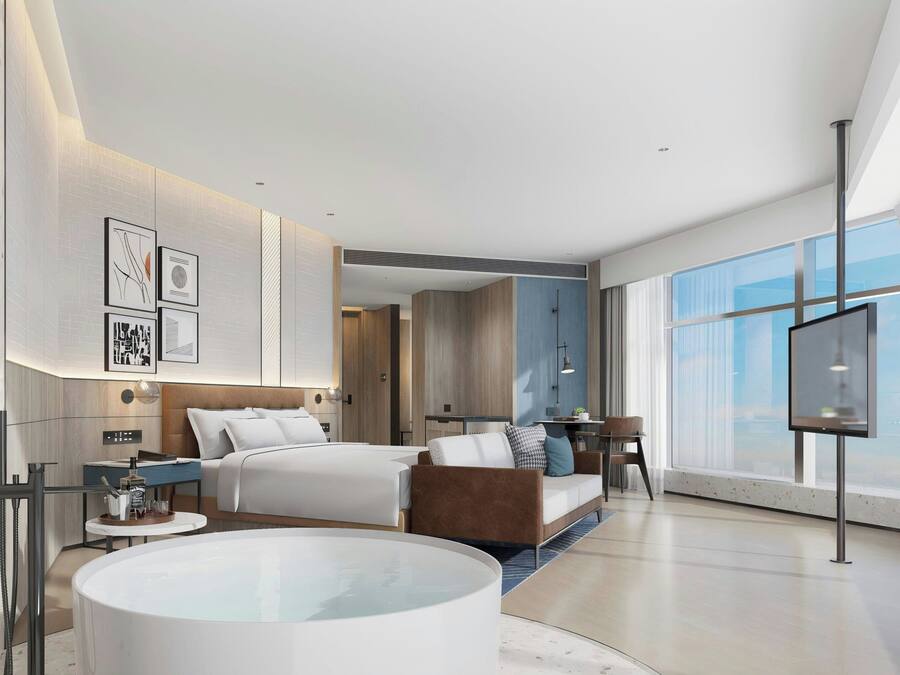 Een moderne hotelkamer met een groot bed, een zithoek, een televisie en een groot raam.