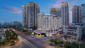 A multi-story hotel with a modern design, located in a high-rise urban area with surrounding high-rise buildings.