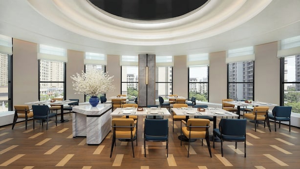 A modern dining area with round tables, chairs, and a central decorative vase.
