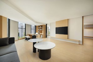 A modern living room with a sofa, two round tables, a TV, and a bookshelf.