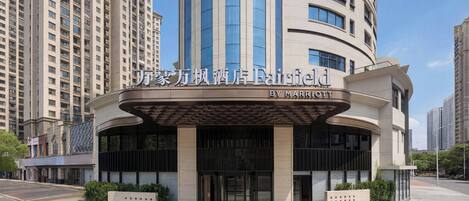 A modern hotel entrance with a curved facade, large glass windows, and a prominent sign.