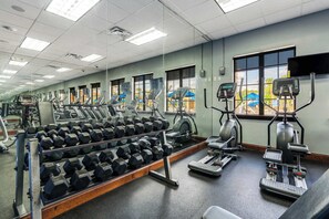 Ein Fitnessstudio mit Laufbändern, Crosstrainern und Kurzhanteln.