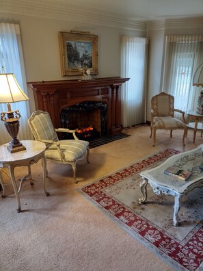 A living room with a fireplace, a table, two chairs, and a coffee table. - A Supreme Stay in Motown star Florence Ballard's Home (Detroit)