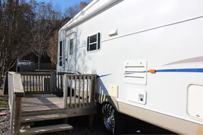 Ein weißer Wohnmobil mit blauem Streifen, einer Tür, einem kleinen Fenster und einer Stufe zum Deck.