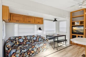 Ein kompaktes Wohnmobil-Interieur mit einer Sitzecke, Esstisch und einer TV-Regal.