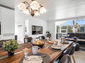 A modern dining area with a wooden table, chairs, and a chandelier. - "Garlef" - 10km from the sea by Interhome (Oksbøl)