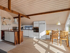 Eine geräumige Küche mit Holzbalken, weißen Schränken und einem Essbereich mit Tisch und Stühlen.