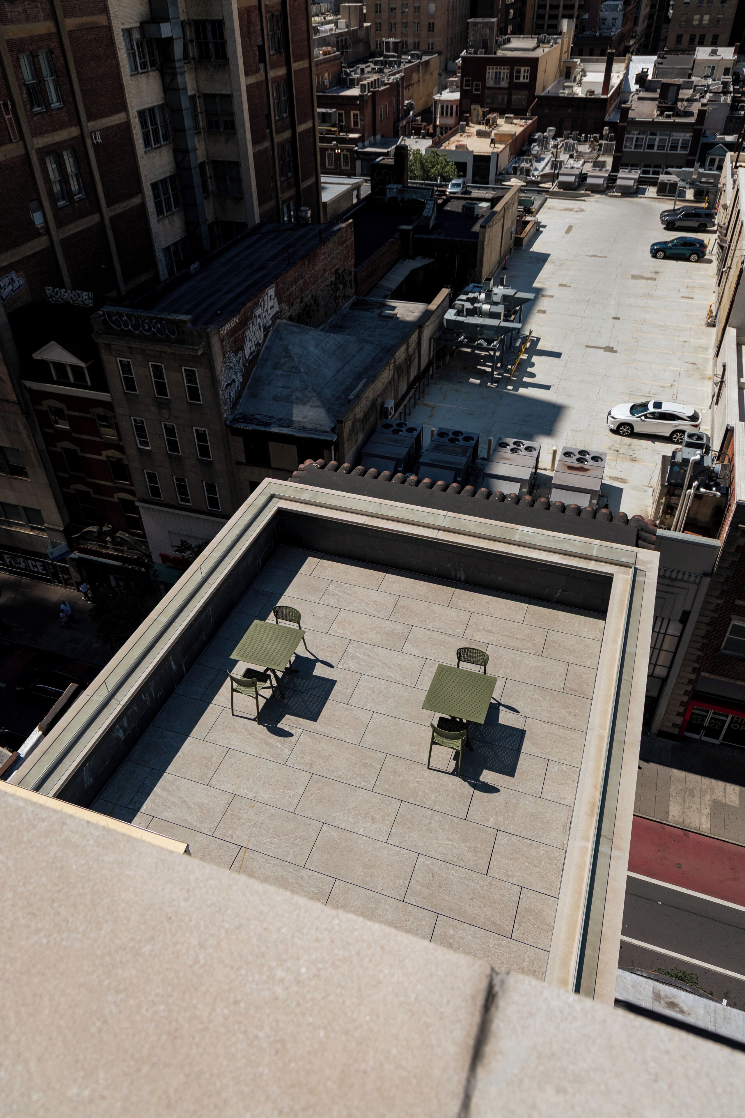 A rooftop terrace with tables and chairs, surrounded by buildings.