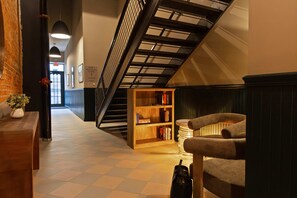 Una escalera con una estantería de madera, un banco y un jarrón con flores.
