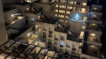 Un immeuble résidentiel à plusieurs étages, doté de balcons, d’escaliers et offrant une vue sur la ville la nuit.