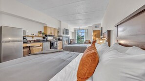 Una habitación de hotel moderna con dos camas, un kitchenette y un balcón con vistas.