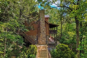 Eine Blockhütte mit einem Steinkamin, einer Holztreppe und einer Veranda.